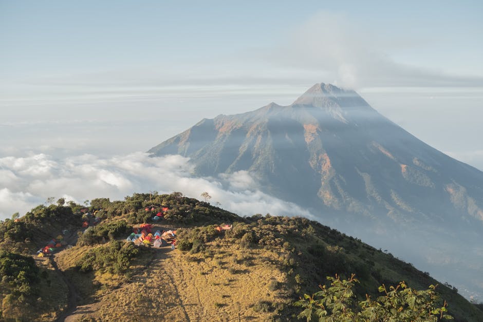 View of Mount Merapi with campsite amidst sea of clouds at sunrise.
